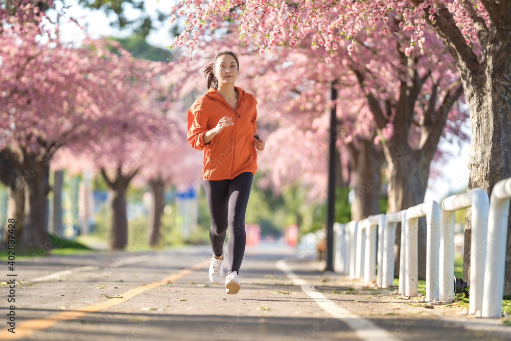 亚洲女性早上锻炼她在樱花公园跑步。
