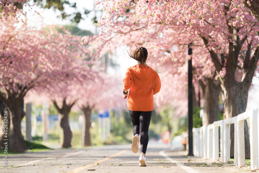亚洲女性早上锻炼她在樱花公园跑步。