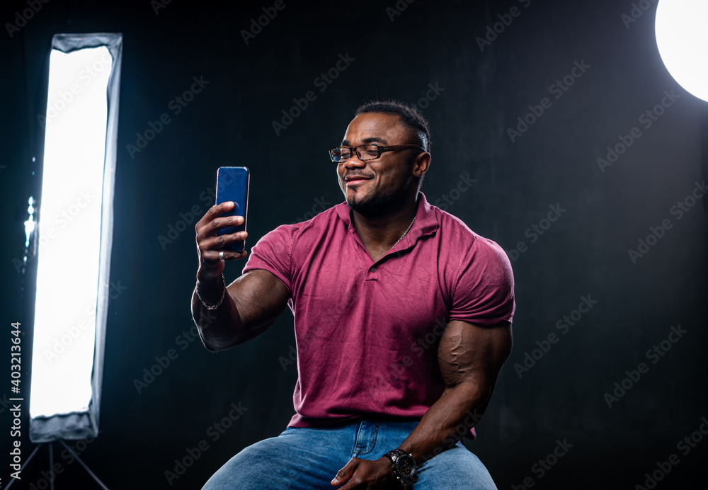 Young handsome african american talks over video connection on black studio background. Led lamps in
