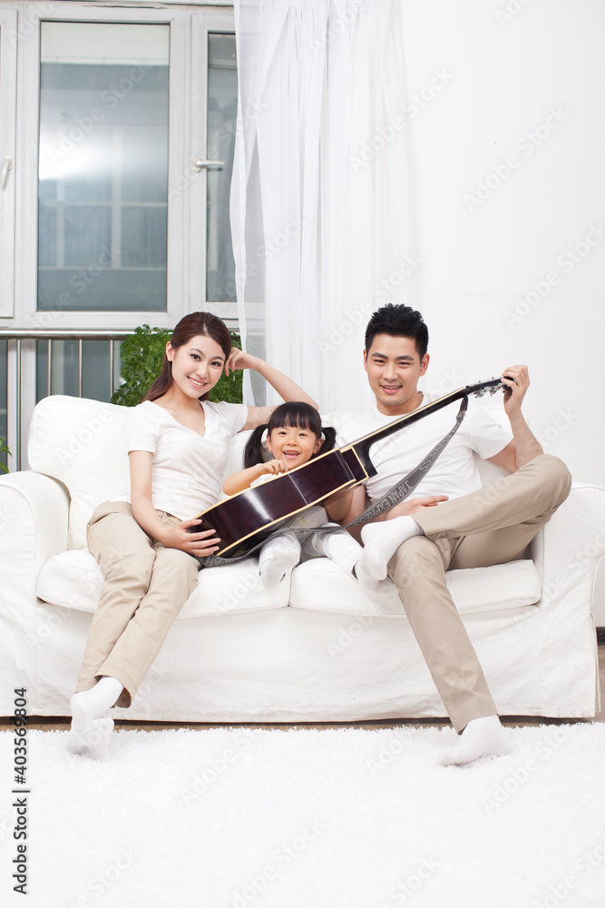年轻的家庭在客厅里弹吉他