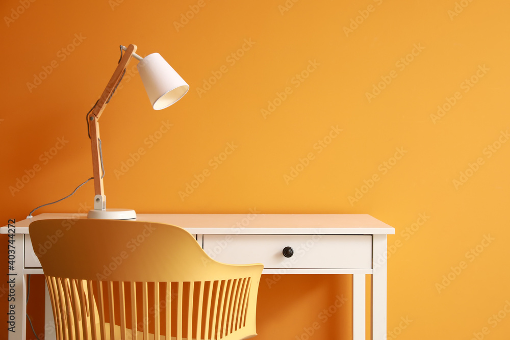 靠近彩色墙的带灯和椅子的现代桌子