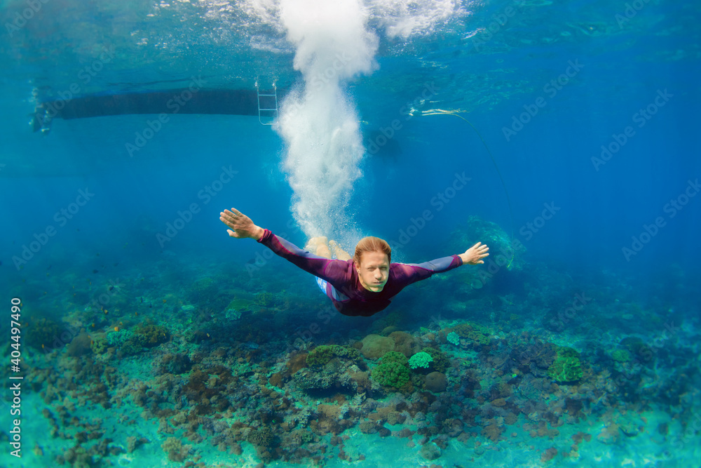 活跃的青少年男子在热带珊瑚礁游泳池中跳到水下潜水。旅行生活方式，水上运动