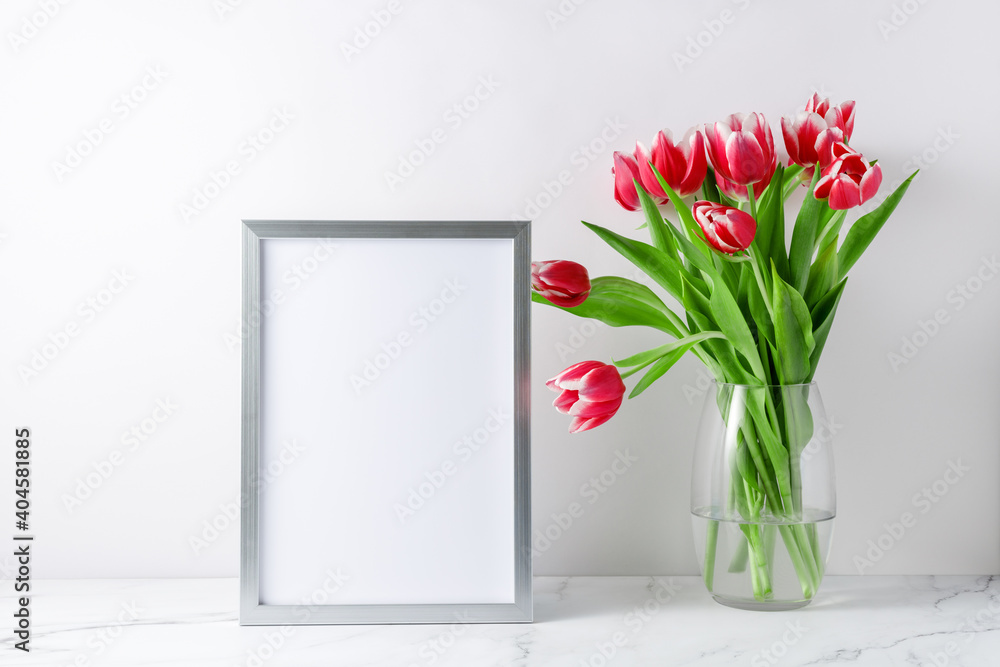 玻璃花瓶和空海报或相框模型中盛开的粉白色郁金香花束