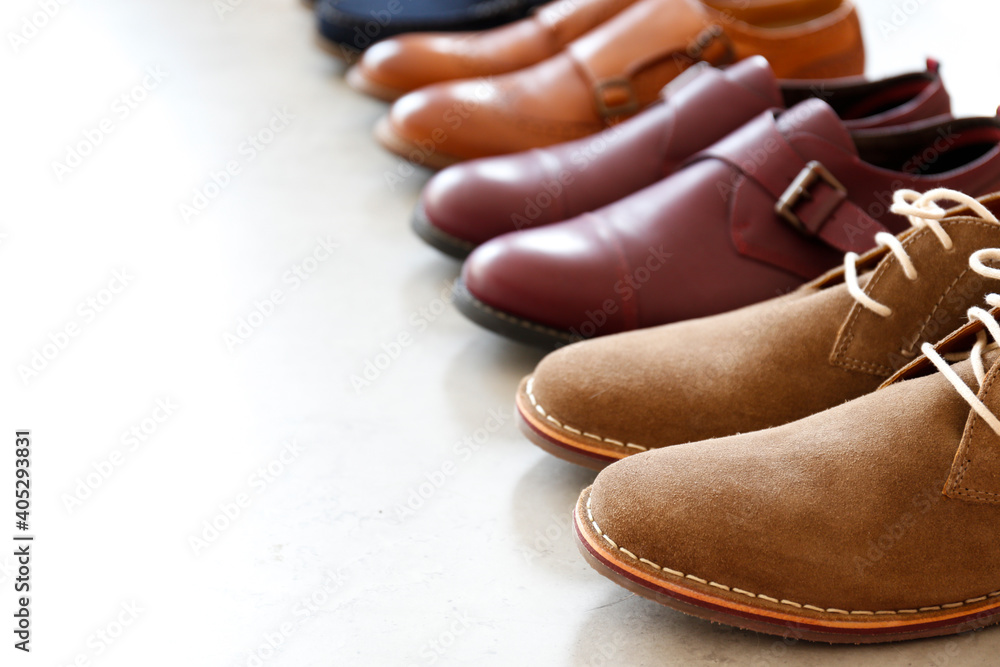 Bunch of different style mens shoes in a row isolated on white background. Close up shot chukka boo