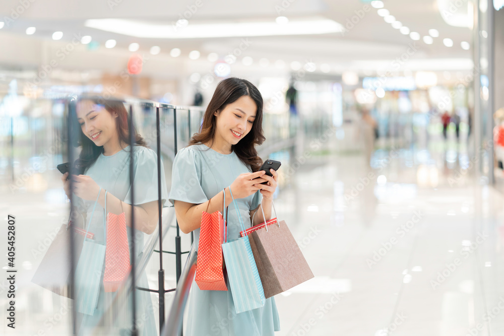 年轻女孩在商场购物并使用手机