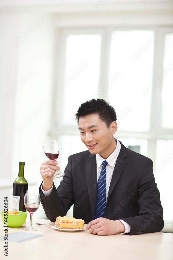 拿着一杯葡萄酒坐在桌子旁的商人画像