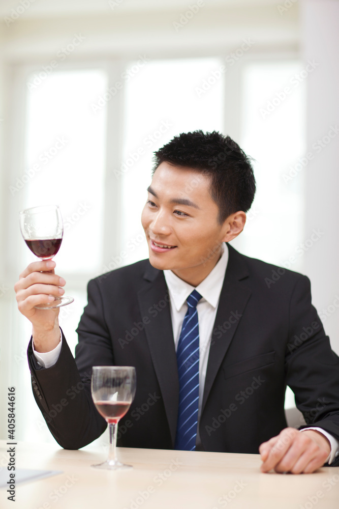 拿着一杯葡萄酒坐在桌子旁的商人画像