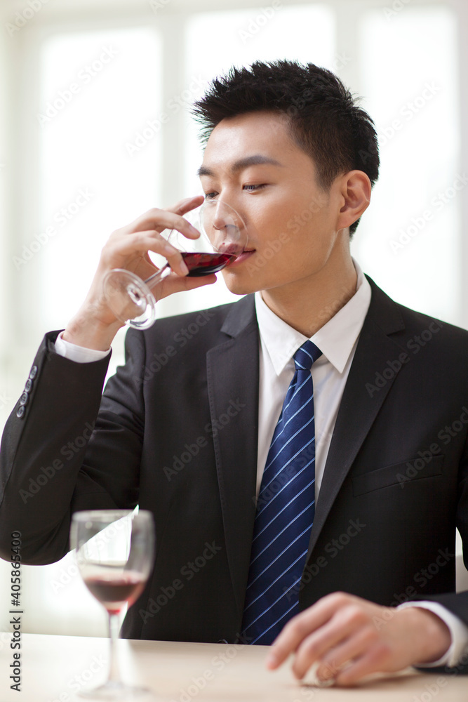 坐在桌子旁喝着一杯葡萄酒的商人画像