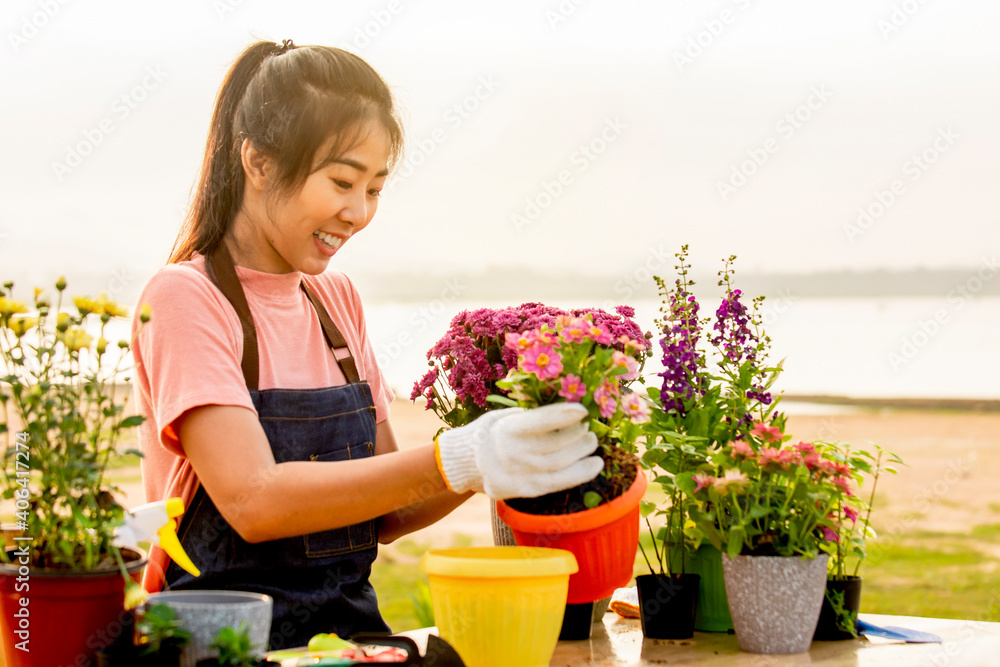微笑的亚洲年轻女子戴着手套在户外花园种花的肖像