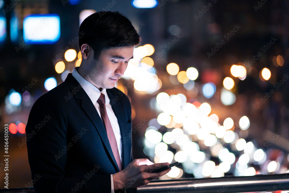 亚洲年轻商人使用手机，站在城市的户外。