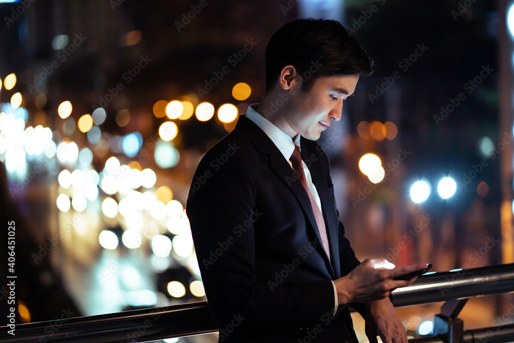 亚洲年轻商人使用手机，站在城市的户外。