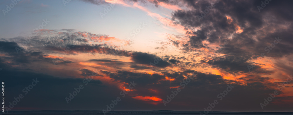 Dramatic gloomy panorama of bright saturated sunset with many dark clouds