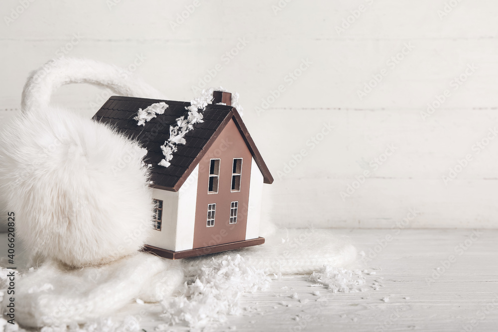 Figure of house, snow and warm clothes on white wooden background. Concept of heating season