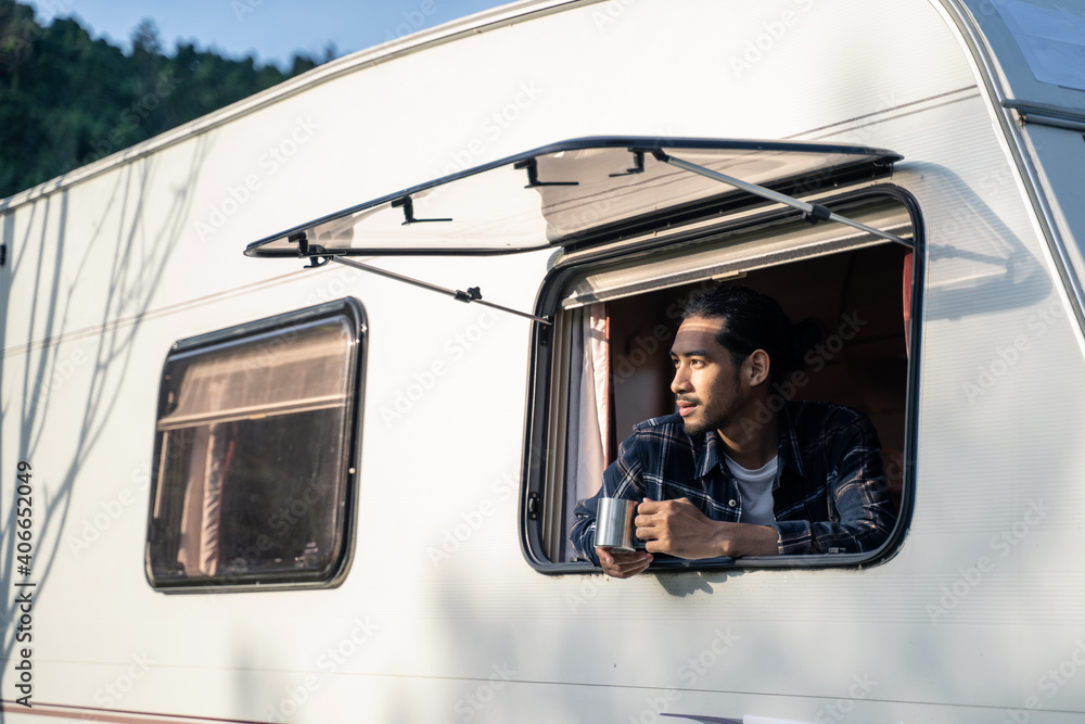 亚洲年轻帅哥打开露营车的窗户，喝咖啡