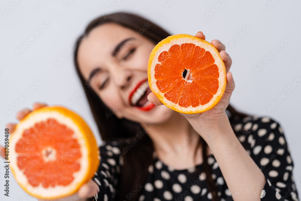 年轻的美女手拿橙子片在白色背景下微笑。健康快乐
