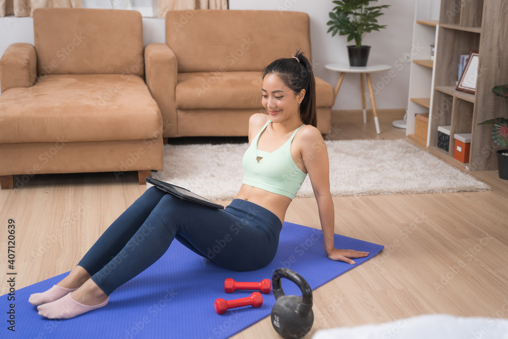 亚洲女性观看平板电脑家庭锻炼课程