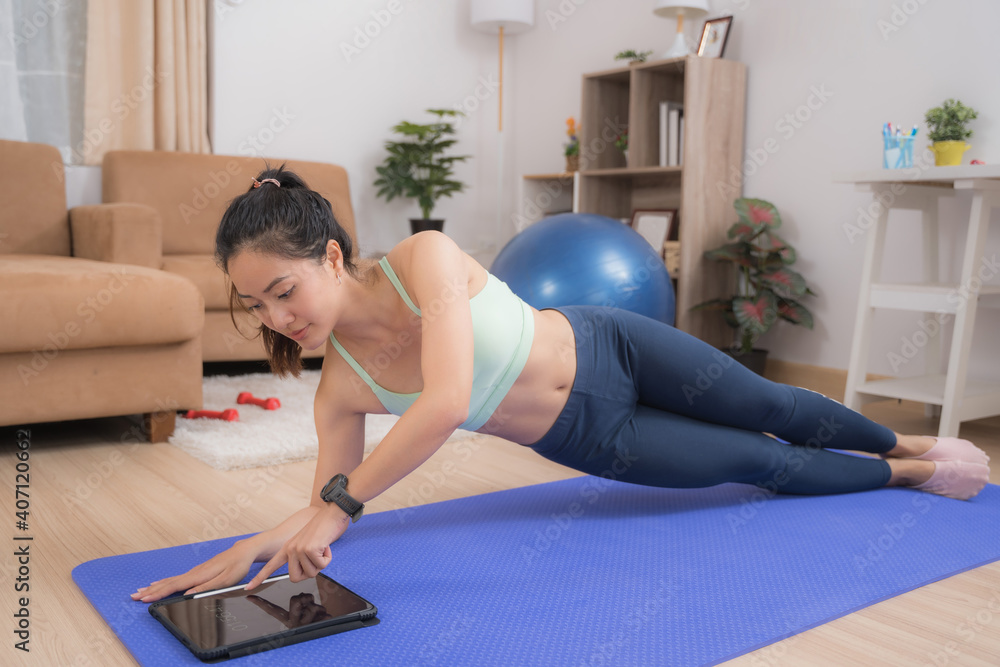 亚洲女性在家锻炼，她做侧平板和停止时间。