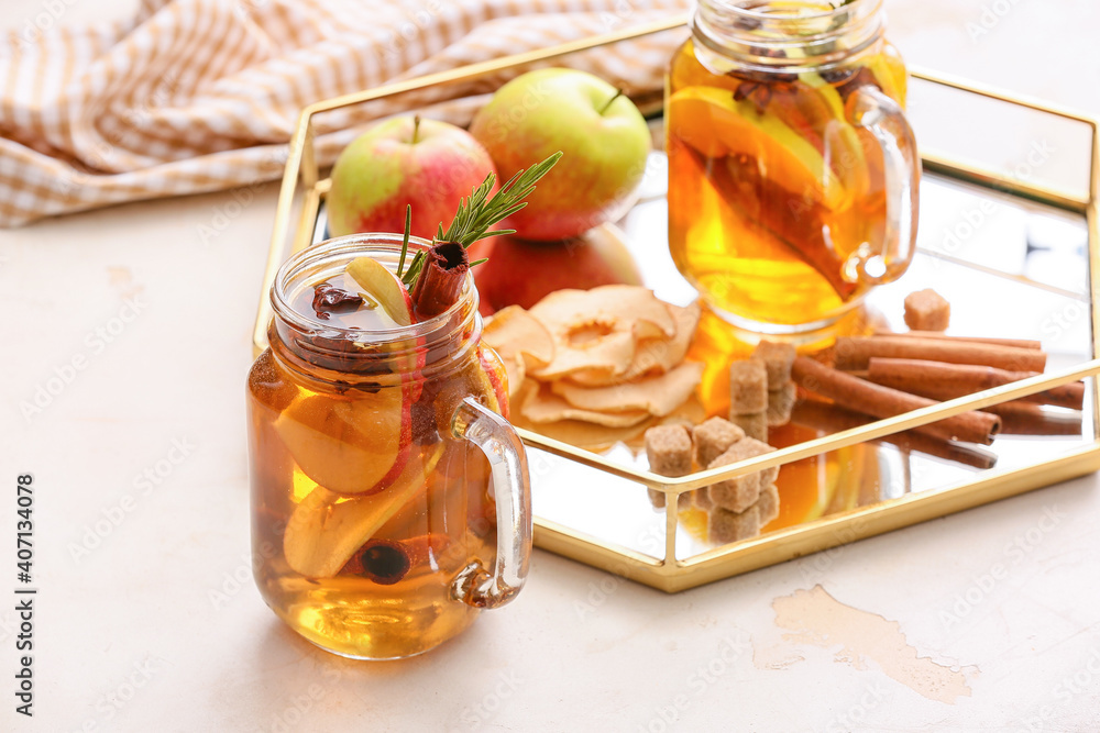 在浅色背景下，用梅森罐装着香料和苹果片的美味饮料