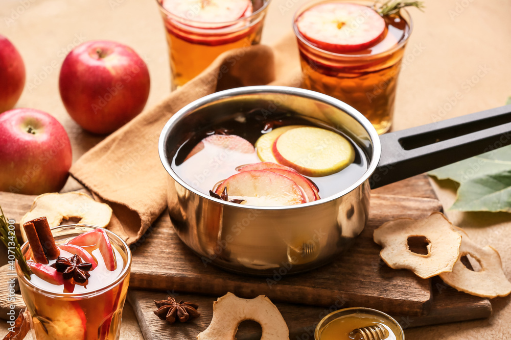 在烹饪锅和玻璃杯中加入香料和苹果片的美味饮料