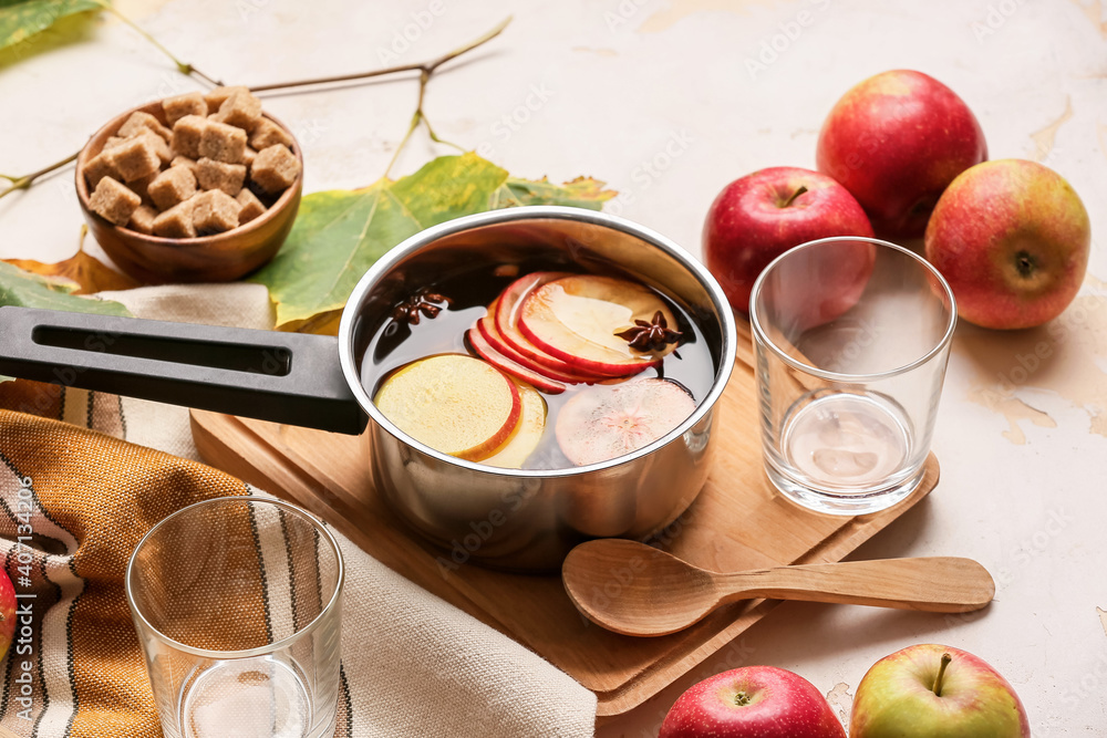 清淡背景下，在烹饪锅中加入香料和苹果片的美味饮料