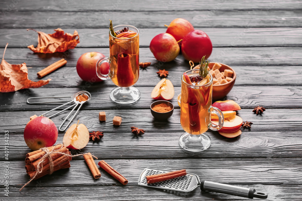 美味的饮料，在深色木质背景下的杯子中加入香料和苹果片
