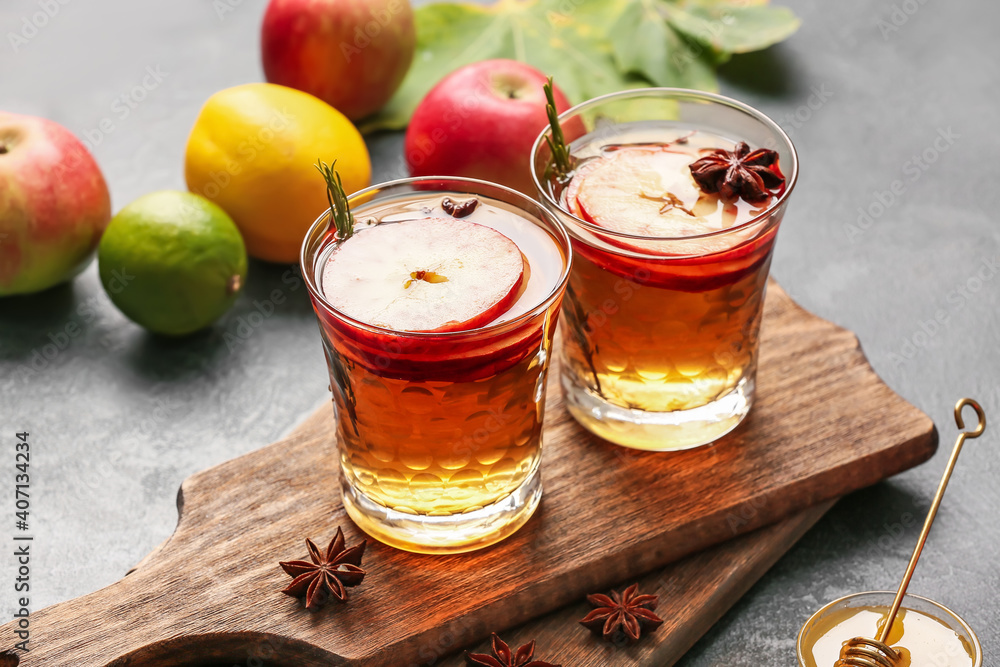 在深色背景下的玻璃杯中加入香料和苹果片的美味饮料