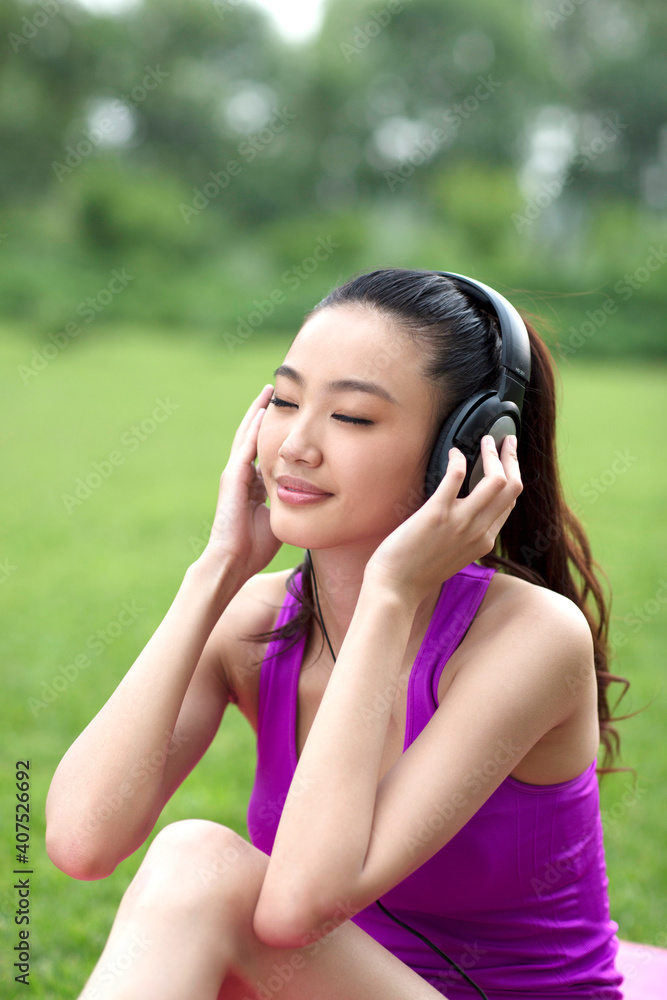 Young woman listening to music on the grass
