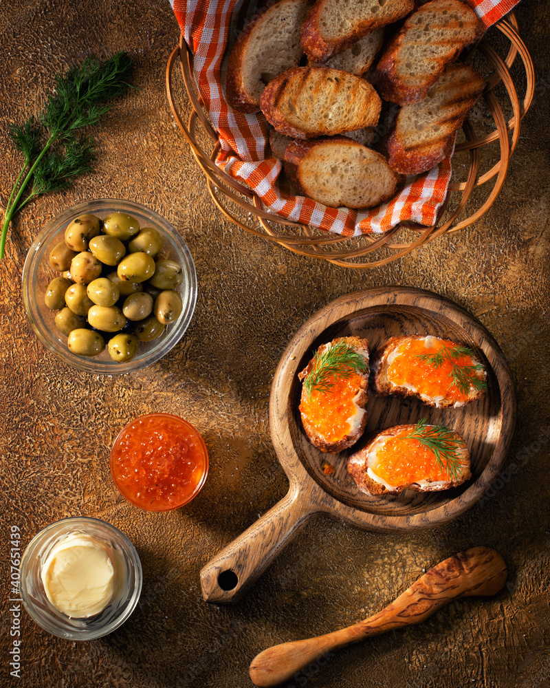 涂有红鱼子酱的面包片与橄榄和黄油一起放在桌子上。烘焙食品概念
