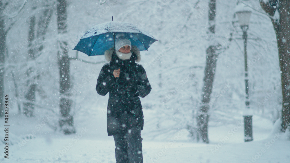 特写，自由度：一名年轻女子在暴风雪中环顾田园诗般的公园。