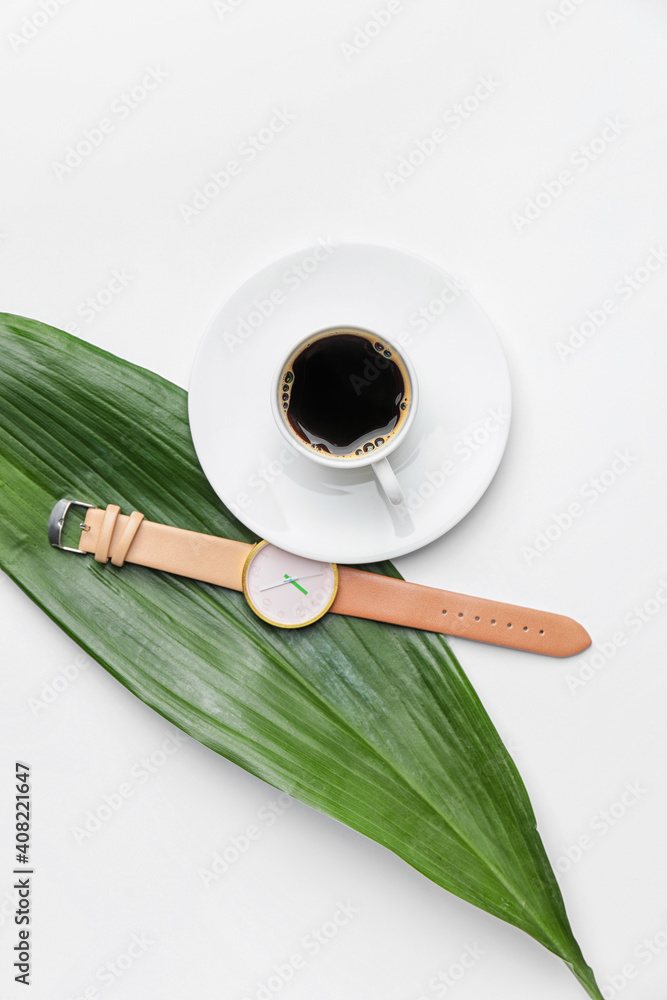 时尚腕表、咖啡杯和白底绿叶