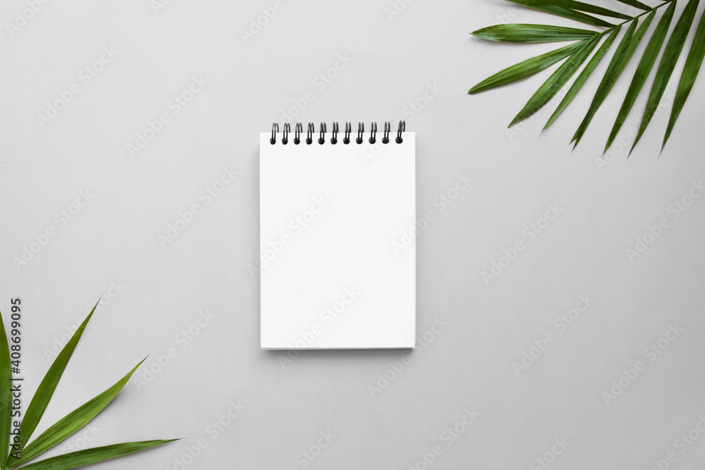 Notepad on gray desk with frame of palm leaves