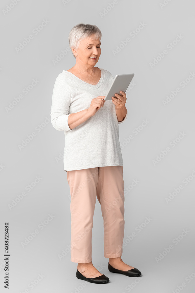 老年妇女在灯光背景下使用平板电脑