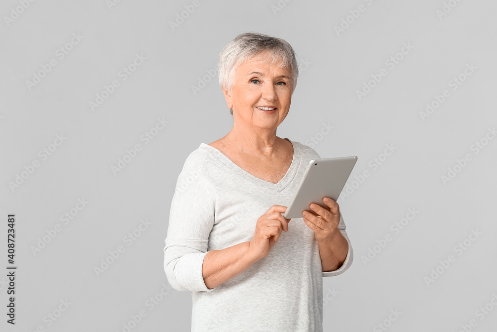 老年妇女在灯光背景下使用平板电脑