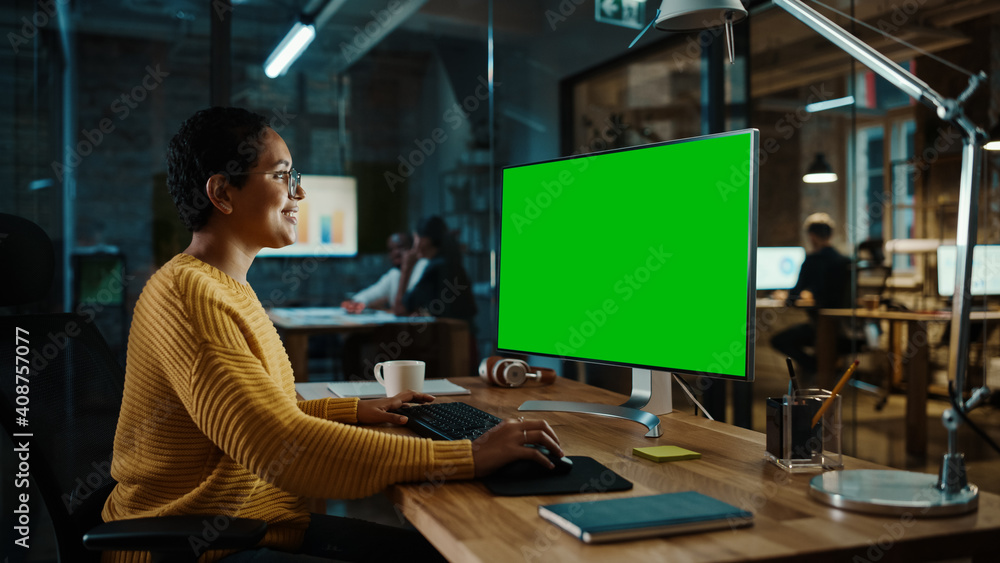 年轻的多民族专家在创意中使用绿屏实体显示器的台式电脑