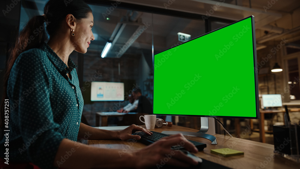 使用绿屏实体显示器的台式电脑工作的中年多民族专家