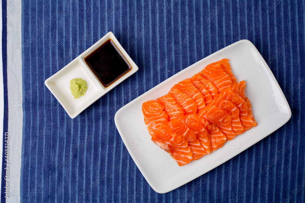 蓝色桌布上的白色日本传统菜肴上的三文鱼生刺身。