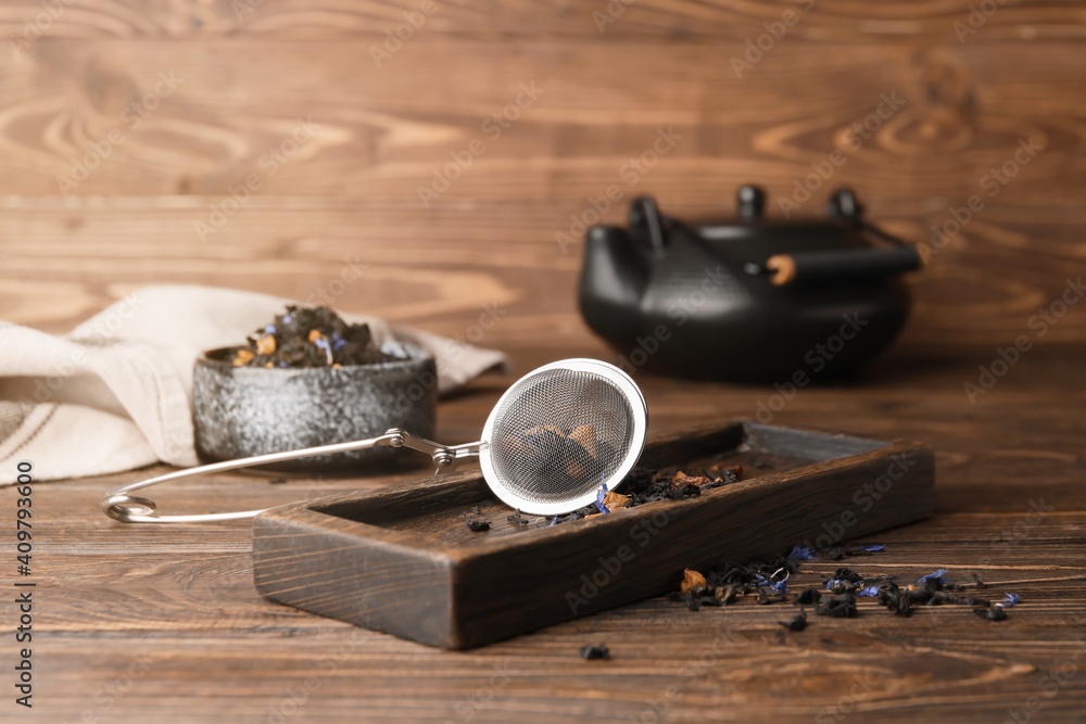 Infuser with dry fruit tea on wooden background