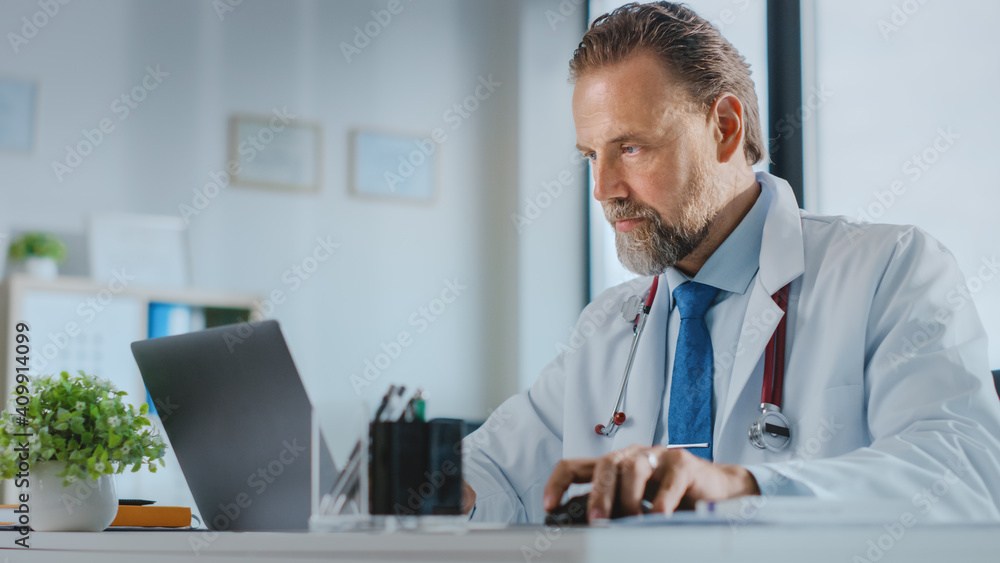 留胡子的中年家庭医生在健康诊所使用笔记本电脑。成功