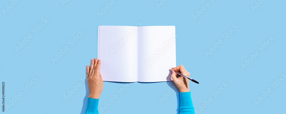Person writing in a notebook from above