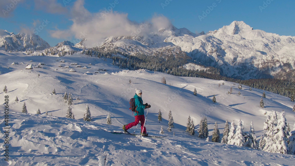 航空：年轻的女游客在滑雪旅行中徒步下山。