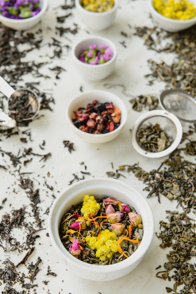 Bowls with different sorts of dry tea leaves on table