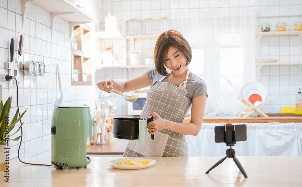 美女肖像亚洲女性评论烹饪油炸土豆食品，使用空中传单录制现场视频
