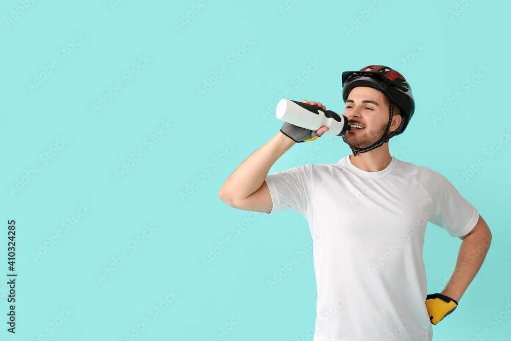 男骑自行车的人在彩色背景下喝水
