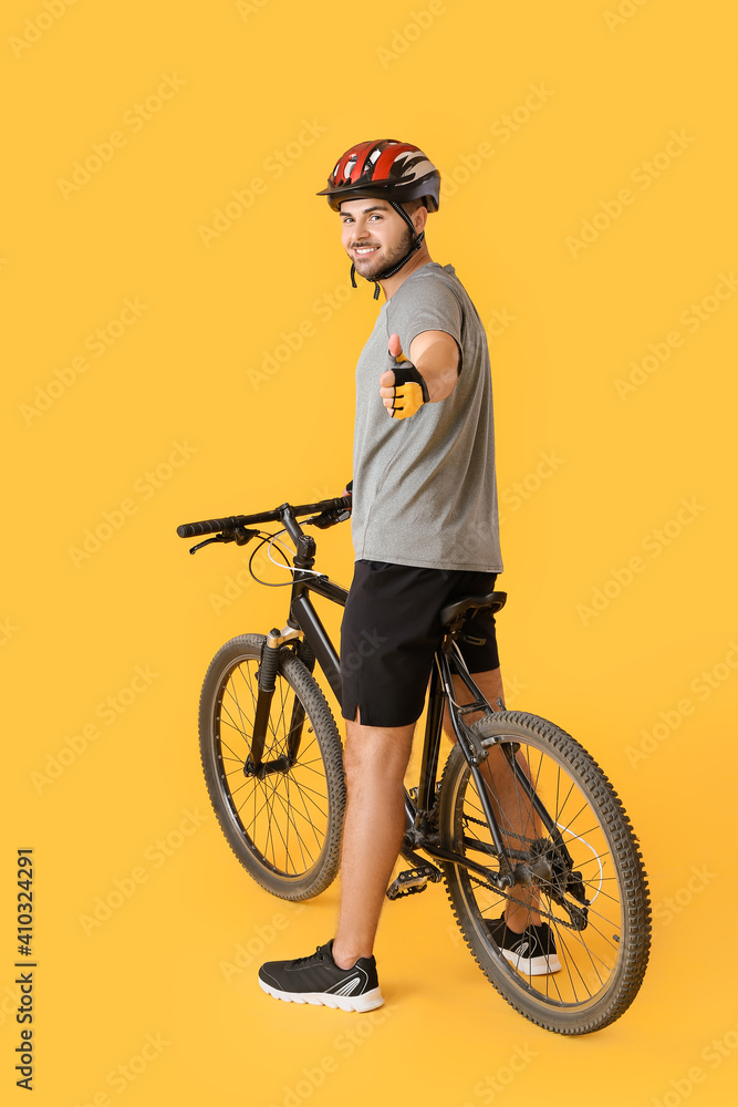 男自行车手在彩色背景上竖起大拇指