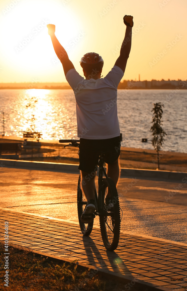 Male cyclist on bicycle raising hands outdoors