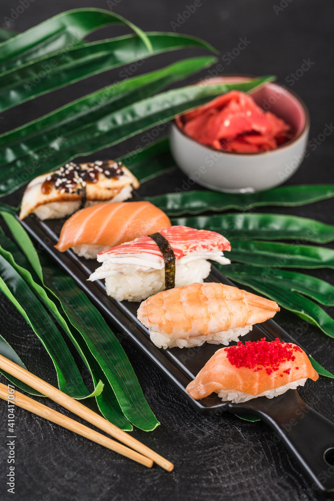Sashimi sushi set with chopsticks and ginger on a dark background close-up.