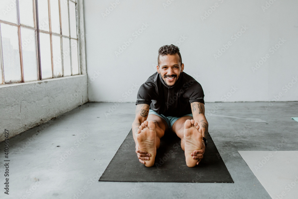 Cheerful man stretching his body on a yoga mat