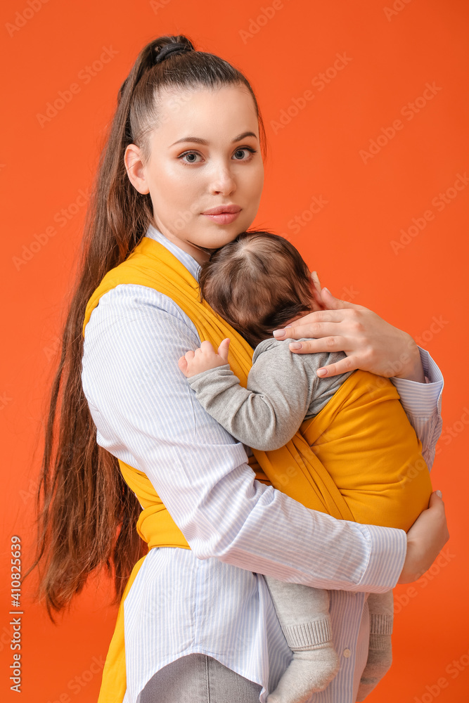 带着小婴儿的年轻母亲穿着彩色背景的吊带