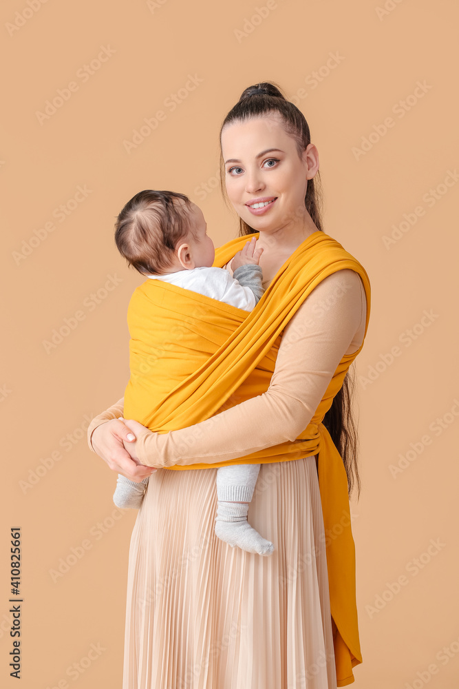 年轻的母亲，带着穿着吊带的小婴儿，背景为浅色