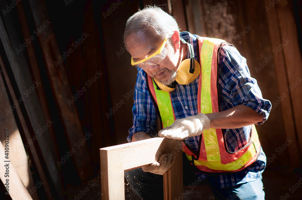木工店里一位上了年纪的木匠正在检查工件是否整齐。木制窗框。